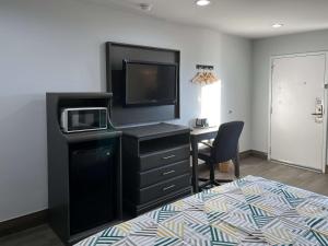 a bedroom with a desk with a tv and a bed at Motel 6 Greenville, NC ECU Medical Center in Greenville
