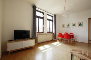 ein Wohnzimmer mit einem Flachbild-TV und roten Stühlen in der Unterkunft Ferienwohnung 3 ANNA IFF in Würzburg