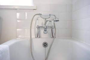 een wit bad met een douche in de badkamer bij Orange Rentals-Free Parking - 4-Bed home near Sefton Park in Liverpool
