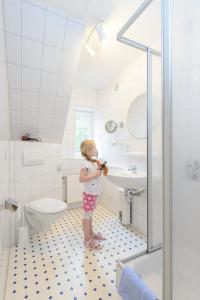 a little girl standing in a bathroom brushing her teeth at Ferienwohnung Kiebitz I in Otterndorf