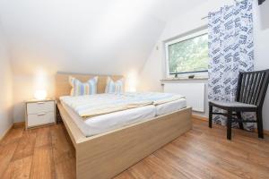 a bedroom with a bed and a chair and a window at Ferienwohnung Kiebitz I in Otterndorf