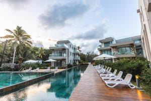 a row of lounge chairs next to a pool at a resort at Brand new, Beachfront Ocean Terraces, Poste Lafayette-Apt-C2 in Poste Lafayette