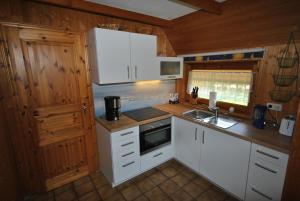 eine Küche mit weißen Schränken und einem Waschbecken in der Unterkunft Ferienhaus Sturmtaucher in Otterndorf