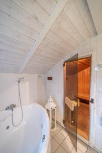 een badkamer met een wit bad en een douche bij Ferienhaus Wyk auf Föhr in Otterndorf