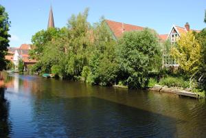 een rivier met bomen en gebouwen en een kerk bij Ferienwohnung Korte in Otterndorf