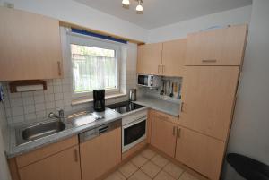 eine kleine Küche mit einer Spüle und einer Mikrowelle in der Unterkunft Ferienhaus Strandperle in Otterndorf