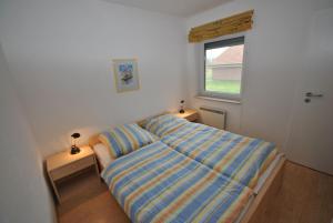 ein kleines Schlafzimmer mit einem Bett und einem Fenster in der Unterkunft Ferienhaus Strandperle in Otterndorf