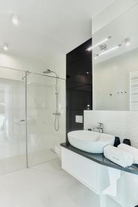 a white bathroom with a sink and a shower at Your Holidays Waves Złote Filary D653 in Międzyzdroje