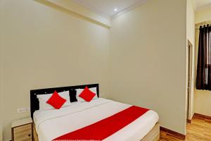 a white bedroom with a bed with red pillows at Super OYO Flagship Sunrise Inn in Lucknow
