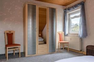 - une chambre avec un placard avec deux chaises et une fenêtre dans l'établissement Ferienwohnung Lerchenweg, à Titmaringhausen