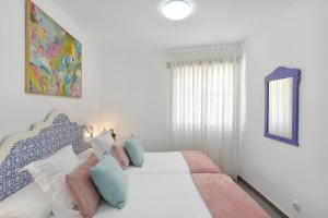 a bedroom with a white bed with blue and pink pillows at Beach Apartment in Playa del Cura 323 in Mogán