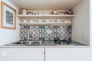 cocina con fregadero y pared de azulejos en Restart Accommodations Farnesina, en Roma