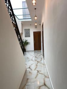 un pasillo con paredes blancas y una escalera con suelo de mármol en Riad Jbara 2 en Rabat