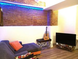 salon z kanapą, telewizorem i gitarą w obiekcie Roós, design loft near the sea. w Barcelonie