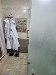 La salle de bains est pourvue d'une douche, de serviettes blanches et de chaussures. dans l'établissement Cozy apartment 2, à Samarcande