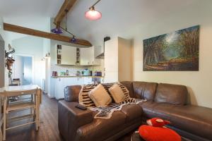 a living room with a brown leather couch and a kitchen at The Stables - 2 bed with large garden and hot tub. in Sway