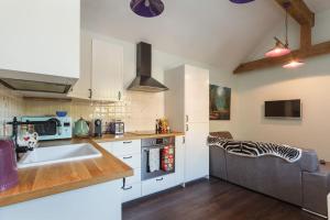 a kitchen with a sink and a couch in a room at The Stables - 2 bed with large garden and hot tub. in Sway