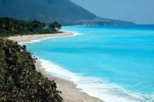 a beach with blue water and a mountain in the background at Agradable Apartamento in Paraíso