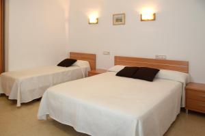 two beds in a hotel room with white sheets at Pension Canadiense in Barcelona