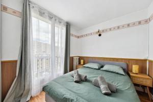 a bedroom with a green bed with a large window at Appartement F3 15 mins à Paris in Aubervilliers