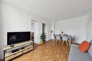 a living room with a television and a table with chairs at Appartement F3 15 mins à Paris in Aubervilliers