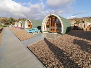 un pequeño edificio verde con un banco azul delante de él en The Wheelhouse Pod No 6, en Letterkenny