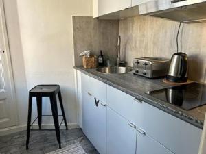 cocina con encimera con fregadero y taburete en Stockholm Loft Haven 3 Beds in a 1- Bedroom Gem - 917, en Estocolmo