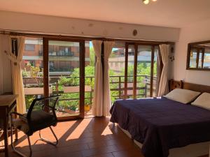1 dormitorio con 1 cama, 1 silla y balcón en Lindo y cómodo departamento en Pinamar - Otilia Residencias en Pinamar
