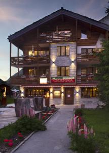 a large wooden building with flowers in front of it at Apart-hotel Channa in Saas-Almagell