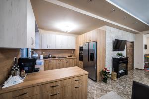 a kitchen with wooden cabinets and a stainless steel refrigerator at Слънчевите Къщи in Banya