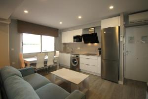 Una sala de estar con un sofá azul y una cocina. en Apartamento CasaTuris en 1ª Línea Muchavista Edificio Voramar C106, en El Campello