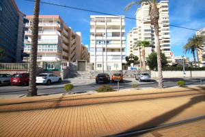 una calle con coches estacionados en una ciudad con edificios altos en Apartamento CasaTuris en 1ª Línea Muchavista Edificio Voramar C106, en El Campello