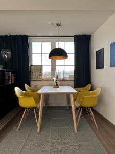 a dining room with a table and yellow chairs at Urban Studio in Buttelstedt
