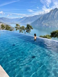 een vrouw in een overloopzwembad met uitzicht op een meer bij Esprit D'Hotel Panoramico in Fonteno