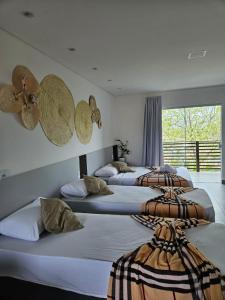 Habitación con 3 camas con sombreros en la pared en Pousada Coração do Rosa en Praia do Rosa