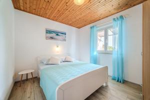 a white bedroom with a bed and a window at Robinson Eda in Murvica