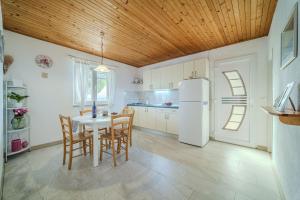 a kitchen with a table and chairs and a refrigerator at Robinson Eda in Murvica