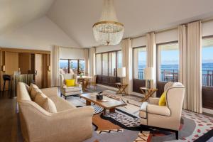 a living room with chairs and tables and windows at Hôtel Royal in Évian-les-Bains