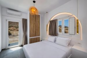 a bedroom with a white bed and two windows at Sonus Mare Beach Apartments, Vourvoulos Beach in Vourvoúlos