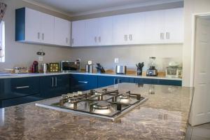 a kitchen with blue cabinets and a stove top oven at House Musantwi in Kroonstad