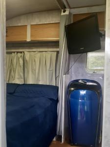 a room with a bed and a tv and a suitcase at Traillertuba Yaveh in Ubatuba