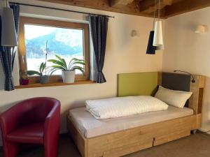 a bed in a room with a chair and a window at Gästehaus Apollo in Schwangau