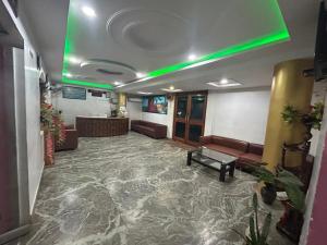 - un hall doté d'une salle d'attente avec canapés et lumière verte dans l'établissement Hotel Maurya Vihar Bodhgaya, à Bodh Gaya