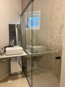La salle de bains est pourvue d'un lavabo et d'une douche en verre. dans l'établissement Praia do Engenho - Apart Lindo e Novíssimo 30m da praia, à São Sebastião