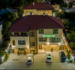 une vue aérienne sur une maison avec des voitures garées devant dans l'établissement Слънчевите Къщи, à Banya