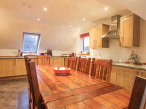 une grande cuisine avec une table et des chaises en bois dans l'établissement Roselea, à Broadford