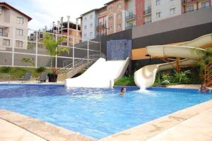a person in a swimming pool with a water slide at Apartamentos em Rio Quente com maravilhosa área de lazer e linda vista in Rio Quente