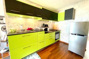 a kitchen with yellow cabinets and a stainless steel refrigerator at Arahea Lagoon flat beachfront with pool facing the sunset Wi-Fi - AC in Paea