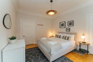 a white bedroom with a bed and a mirror at Beautifully Renovated 2 Bedroom Apartment in Stirling