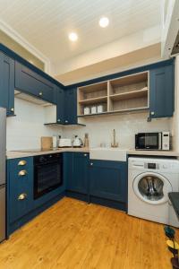 a kitchen with blue cabinets and a washing machine at Beautifully Renovated 2 Bedroom Apartment in Stirling